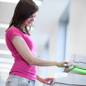 pretty young woman using a copy machine (shallow DOF; color tone